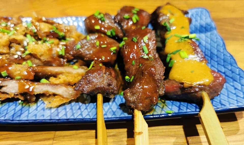 Sticks of grilled meat with a yellow sauce at Kanagawa Restaurant.