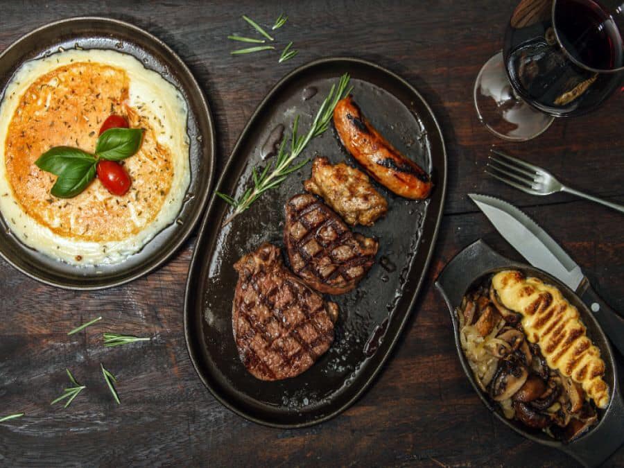 Grilled steak with sausage and other dishes on a table at Asador.
